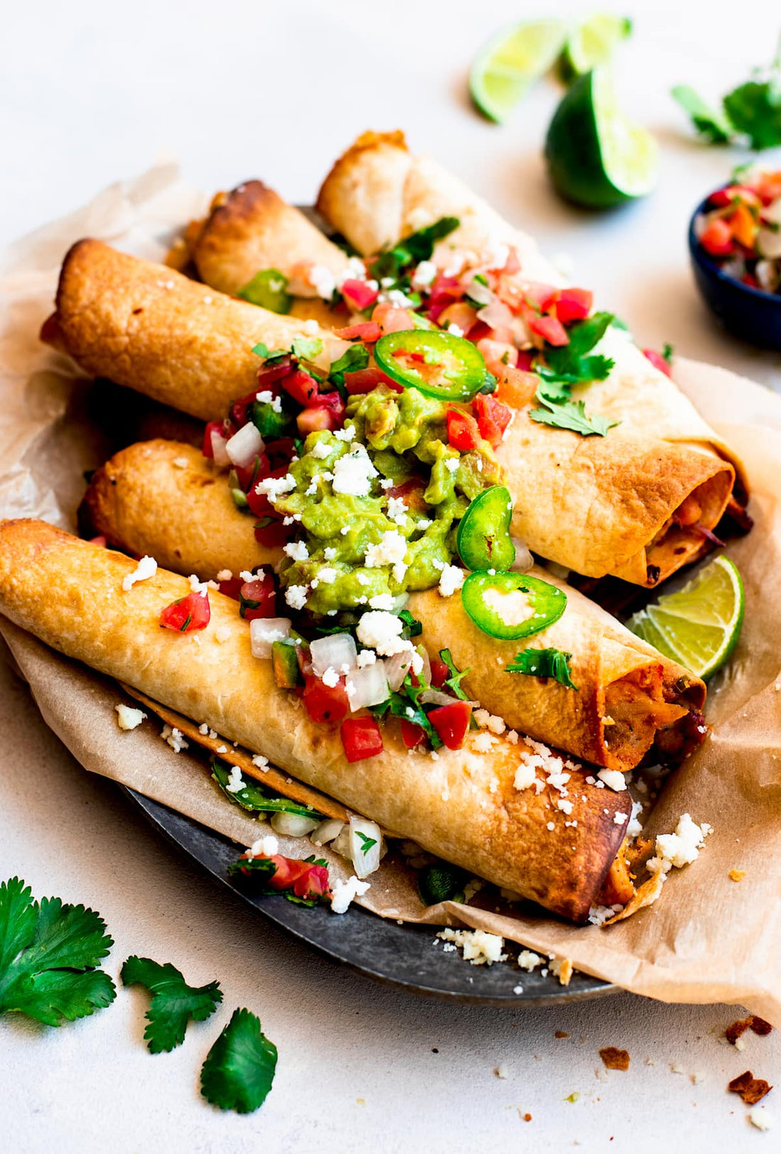 5 baked chicken flautas garnished with veggies on a plate