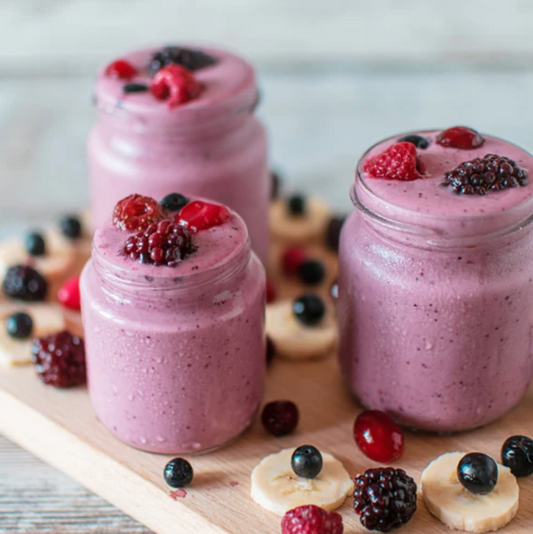 3 mason jars filled with light purple smoothie topped with blackberries and raspberries