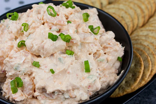shrimp dip in a bowl garnished with thinly sliced green onions
