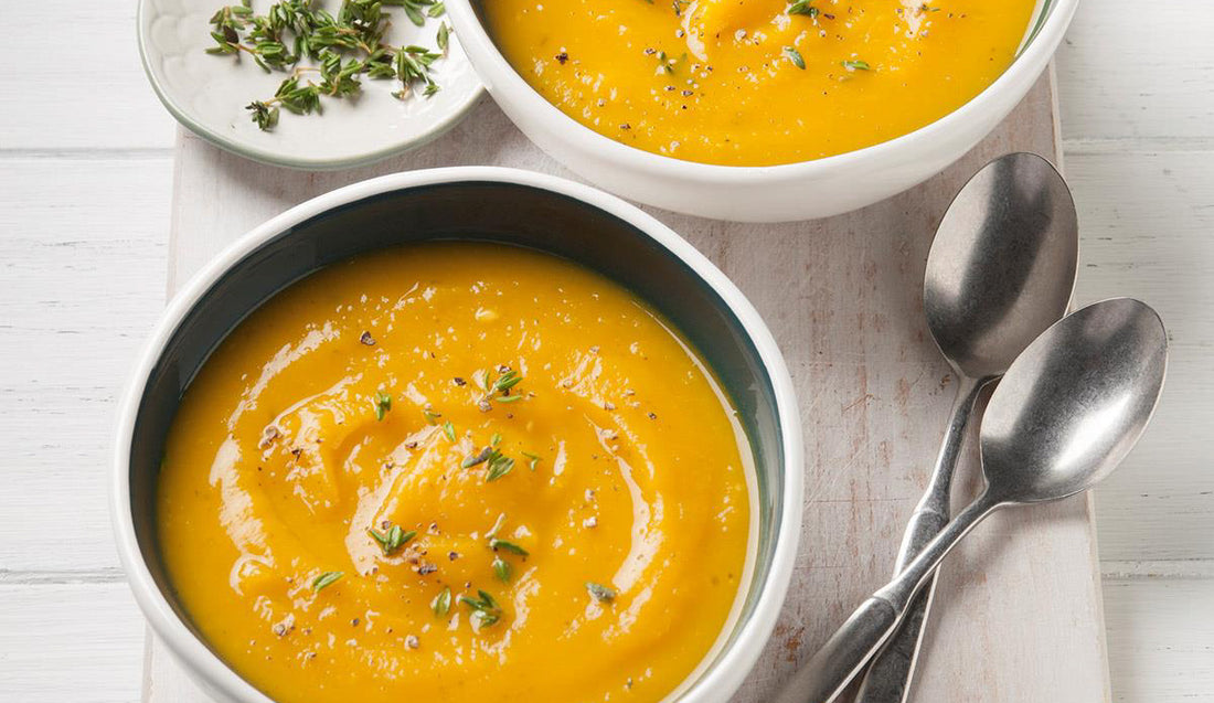 2 bowls of butternut squash soup garnished with herbs