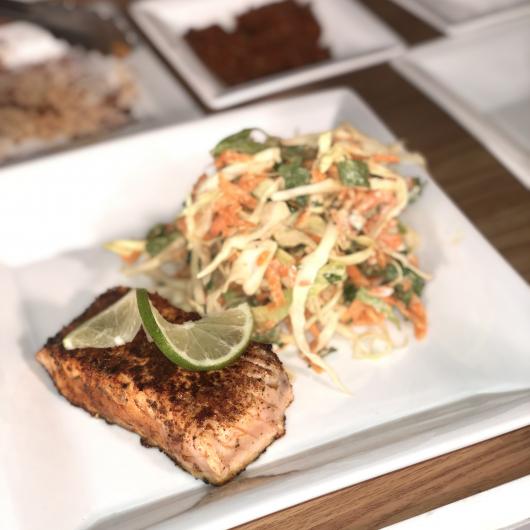 Plate with cooked salmon filet garnished with lime slices with cabbage slaw on the side